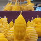 Une chandelle jaune en forme de tête de la déesse Shiva devant plusieurs autres modèles de chandelles jaunes.
